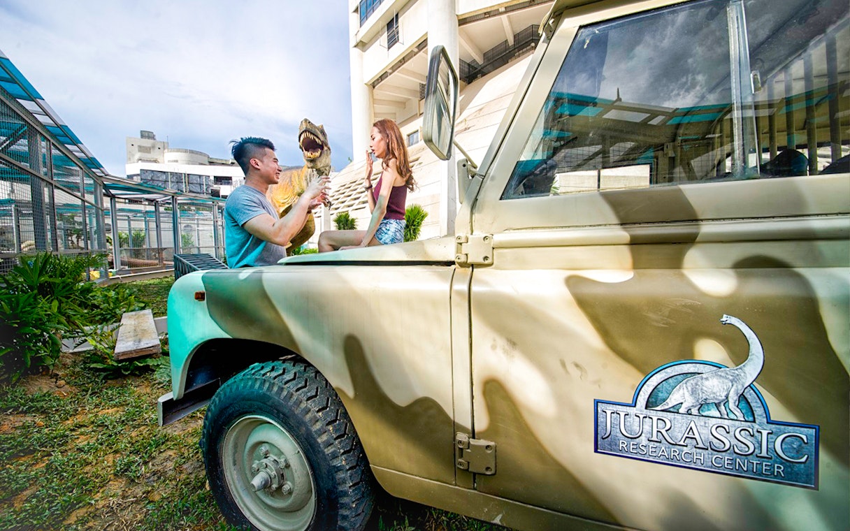 Visitors interacting with a dinosaur model at Jurassic Research Center, Penang.