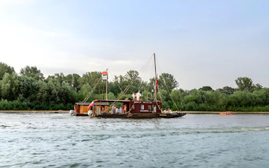 Tourists on a traditional Galar cruise boat on the Vistula River, surrounded by lush greenery.