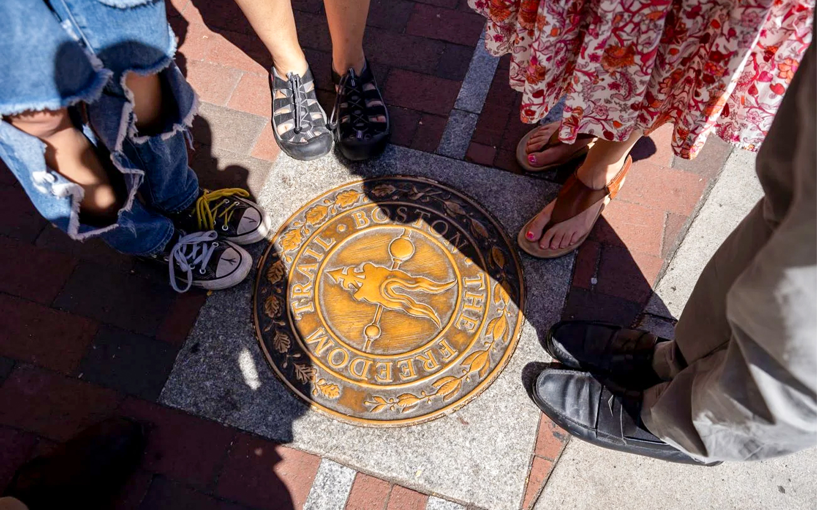 Tourists standing around Freedom Trail marker in Boston.