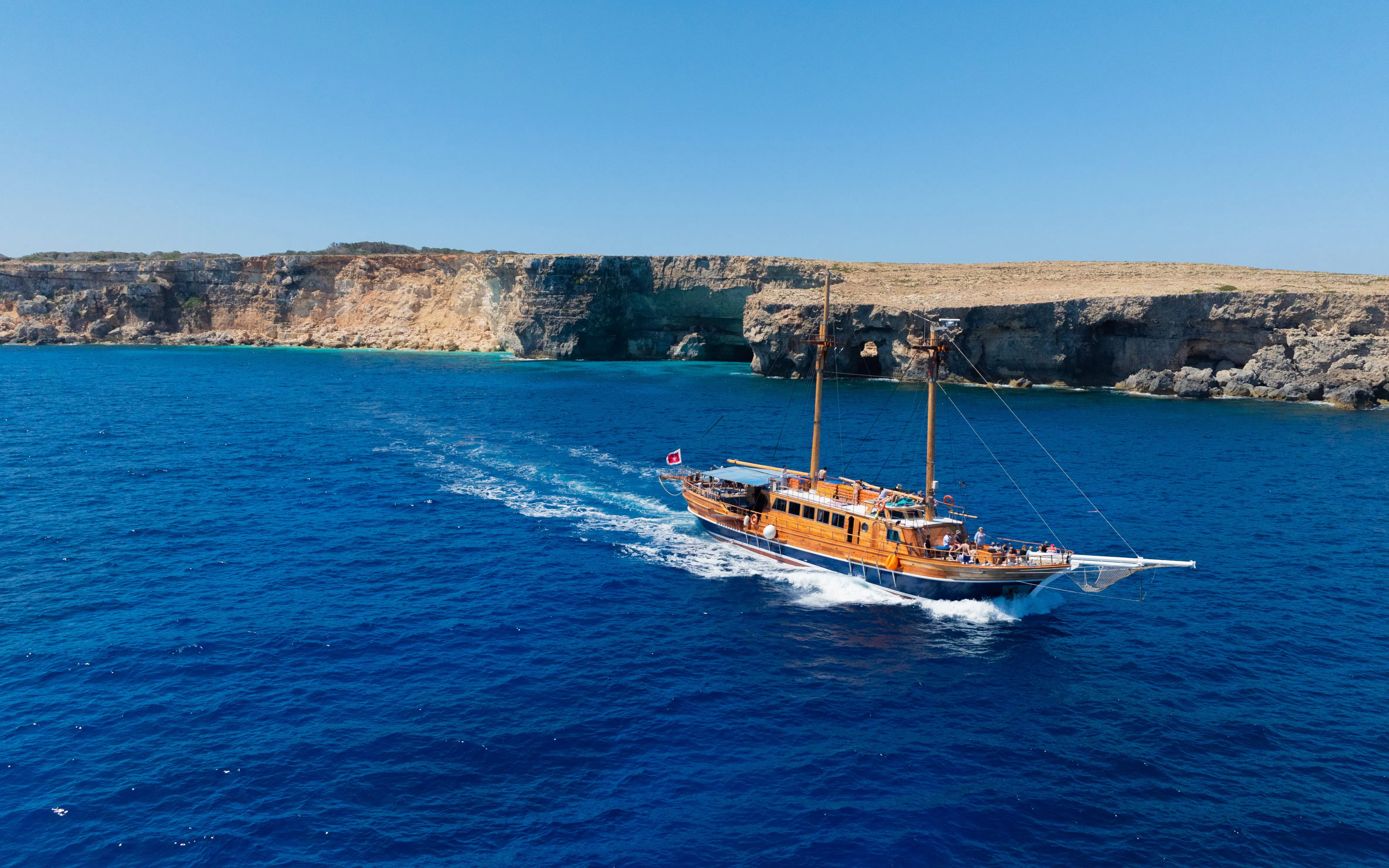 Cruise ship sailing near rocky coastline on Fernandes Gozo & Comino all-inclusive tour.