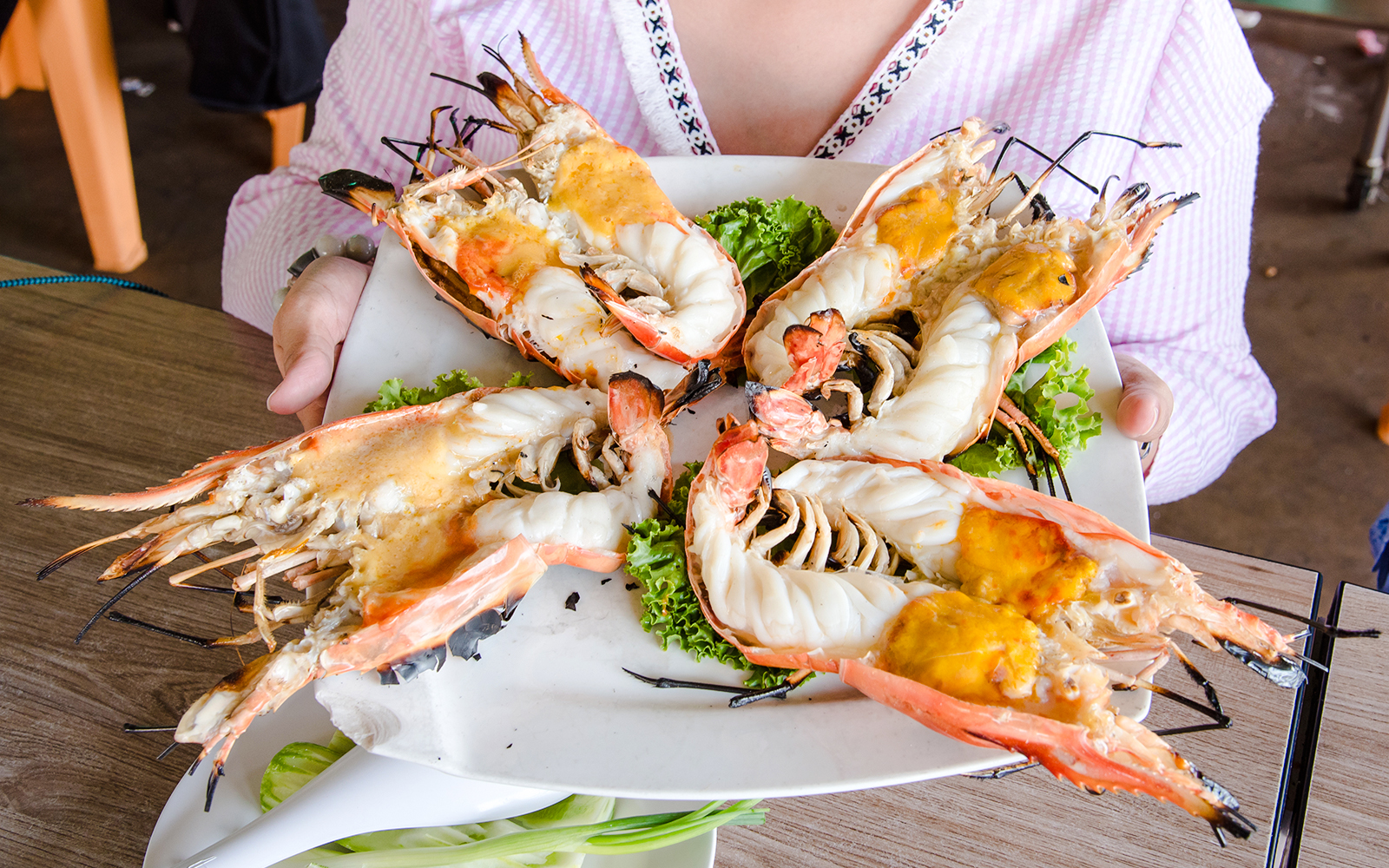 Grilled prawns served on a plate with lettuce at a restaurant.