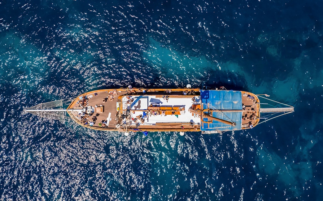 Turkish gulet sailing from Sliema to Gozo and Comino, passengers enjoying lunch on deck.