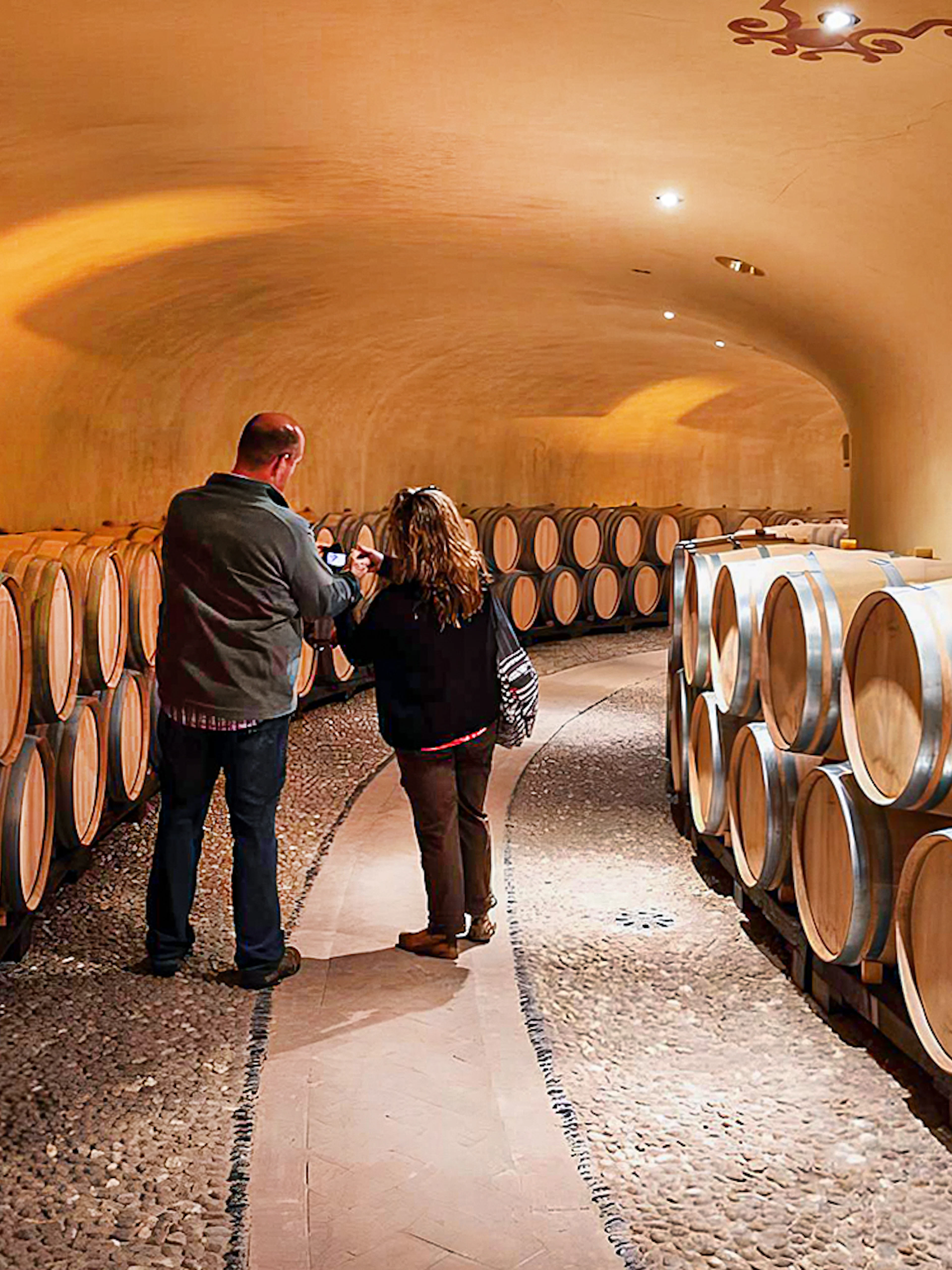 Visitors exploring wine barrels in a Chianti cellar during a guided tour.