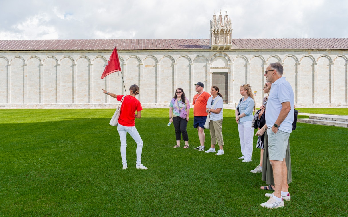 Tour guide with tourists at the Tower of Pisa Complex, Italy.