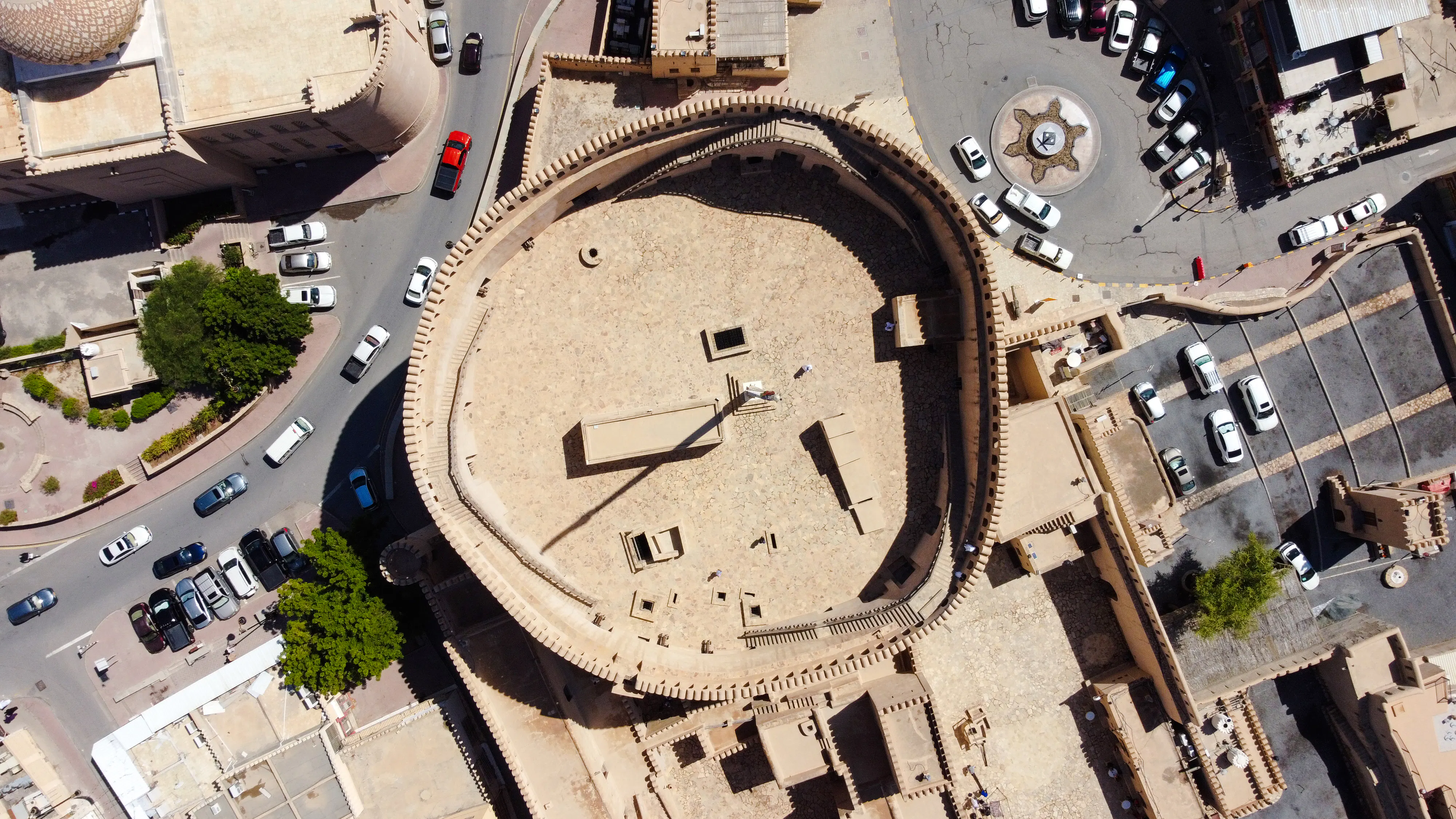 Aerial view of Nizwa Fort in Oman, showcasing its circular design and surrounding cityscape.