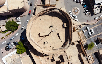 Aerial view of Nizwa Fort in Oman, showcasing its circular design and surrounding cityscape.