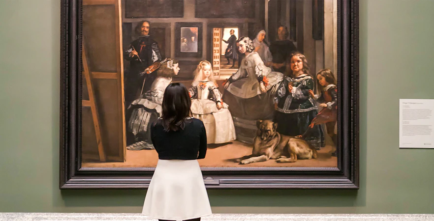 Visitor viewing Velázquez's "Las Meninas" at Prado Museum, Madrid.