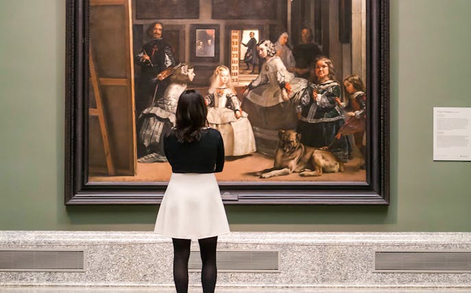 Visitor viewing Velázquez's "Las Meninas" at Prado Museum, Madrid.