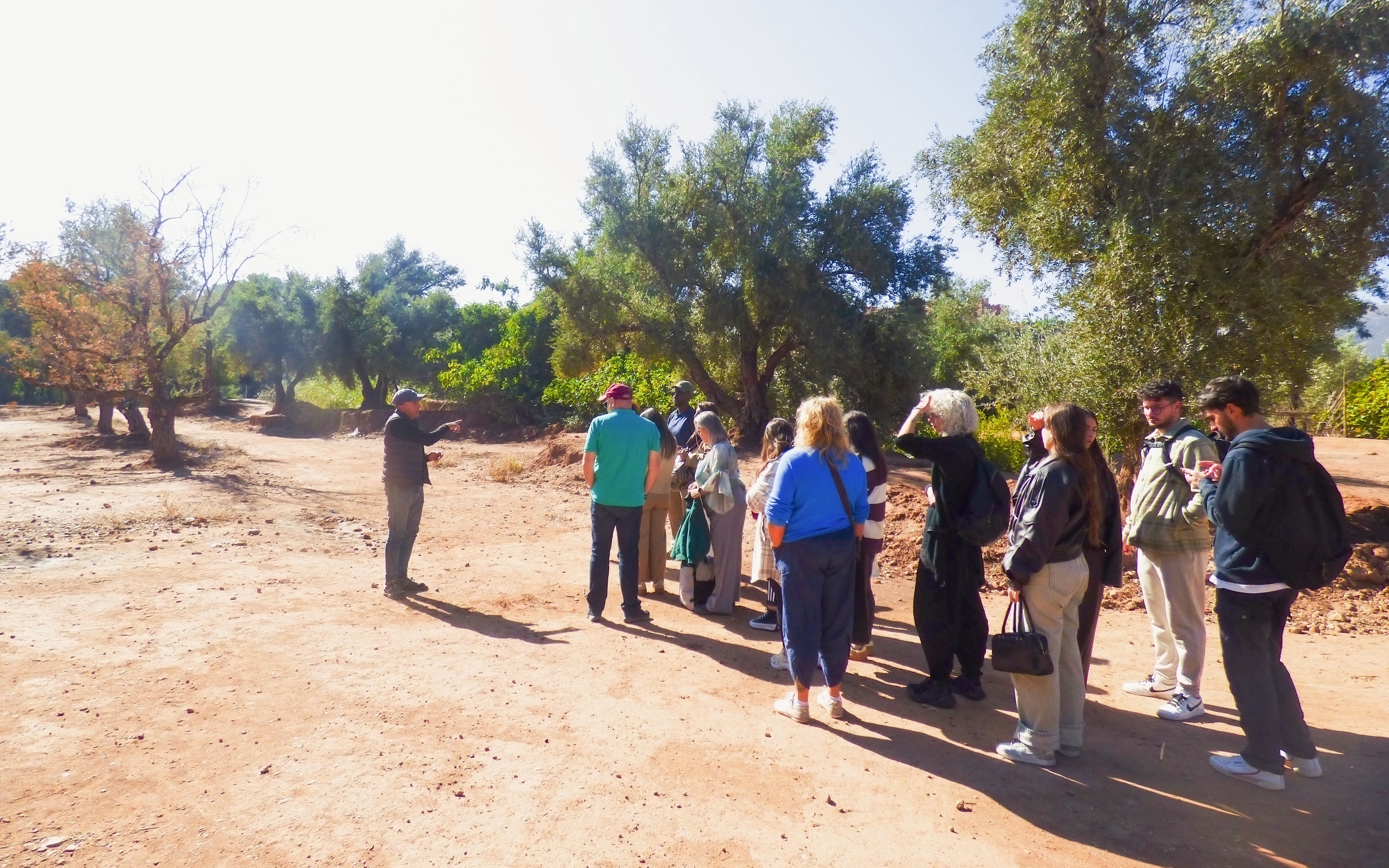 Tourists on guided hike at Ouzoud Waterfalls, Morocco, with a guide explaining the surroundings.