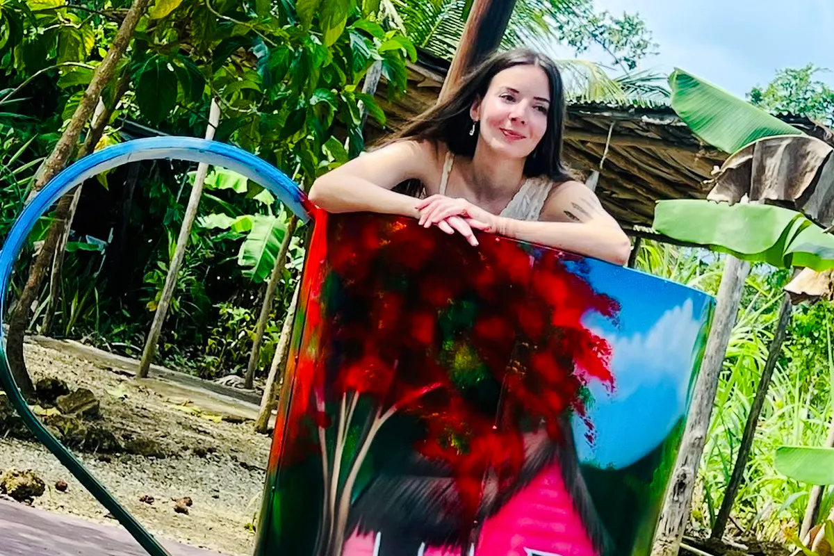 Woman leaning on colorful artwork at Punta Cana artisan market.