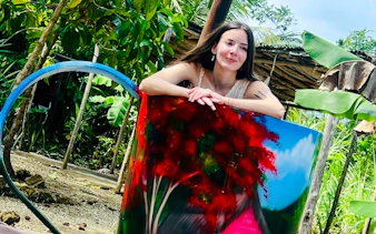 Woman leaning on colorful artwork at Punta Cana artisan market.
