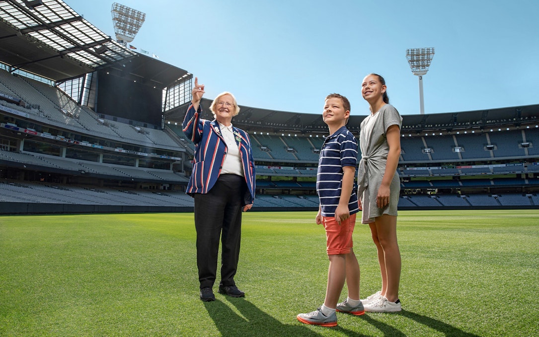 Tour guide with visitors on the field of MCG Stadium during Melbourne sports walking experience.