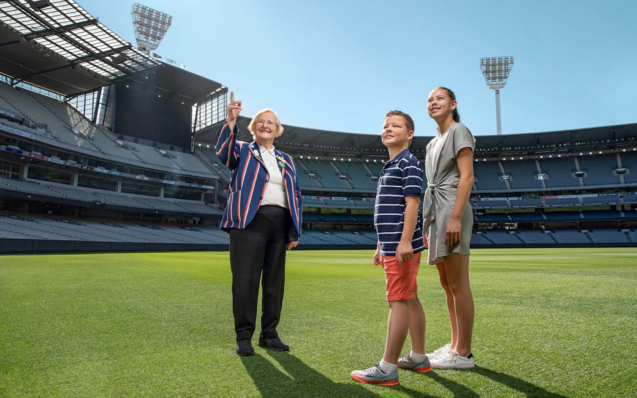 Tour guide with visitors on the field of MCG Stadium during Melbourne sports walking experience.