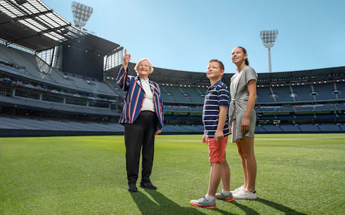Tour guide with visitors on the field of MCG Stadium during Melbourne sports walking experience.