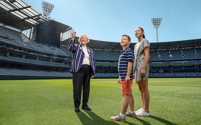 Tour guide with visitors on the field of MCG Stadium during Melbourne sports walking experience.