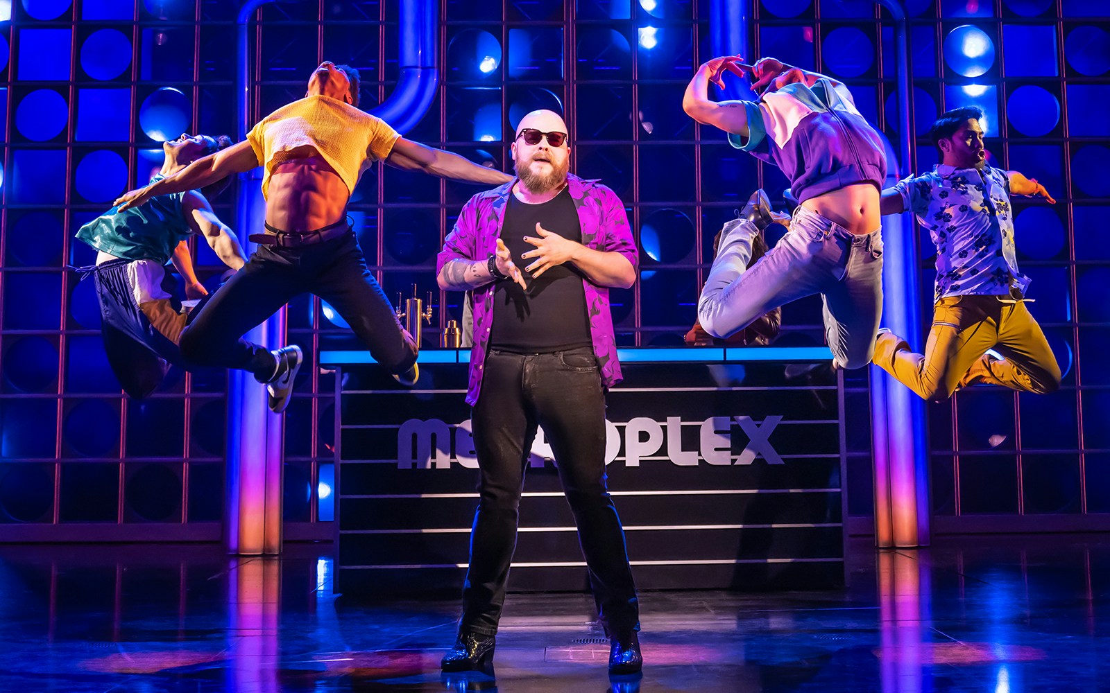 Performers dancing energetically on stage during "The Heart of Rock and Roll" show.