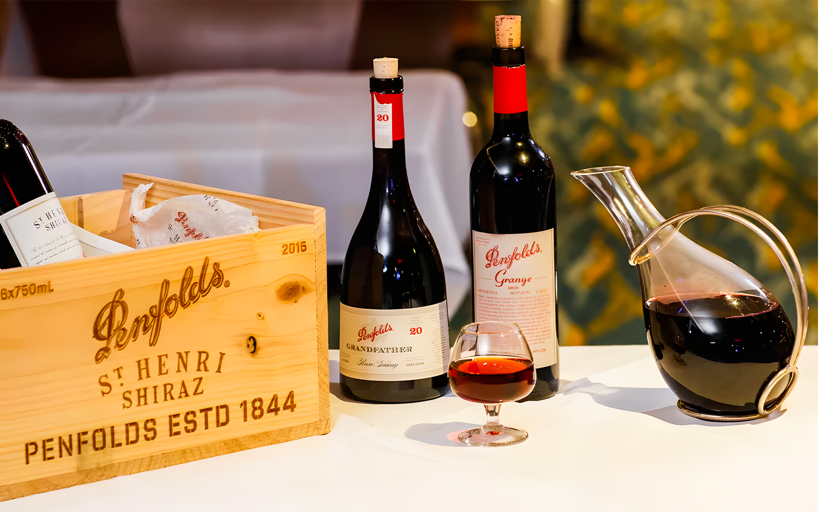 Penfolds wine bottles and decanter with wooden crate on display.