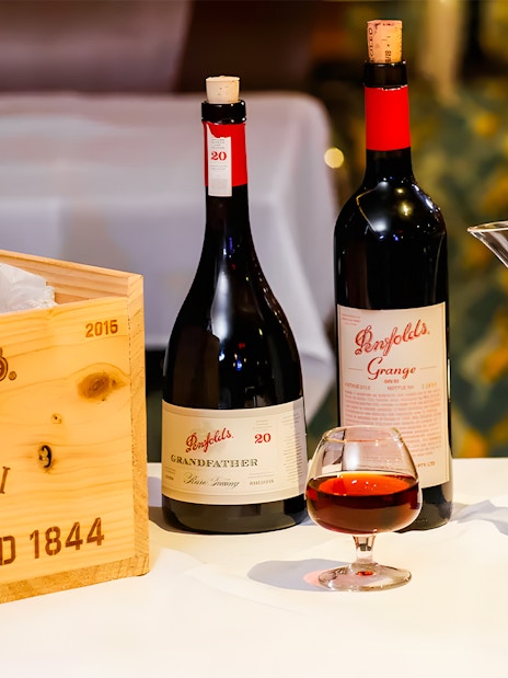 Penfolds wine bottles and decanter with wooden crate on display.