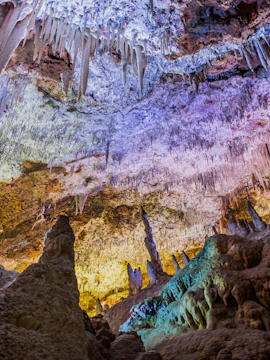 Stalactites and stalagmites in Hams Caves, Mallorca, illuminated with colorful lights.