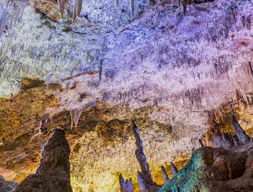 Stalactites and stalagmites in Hams Caves, Mallorca, illuminated with colorful lights.