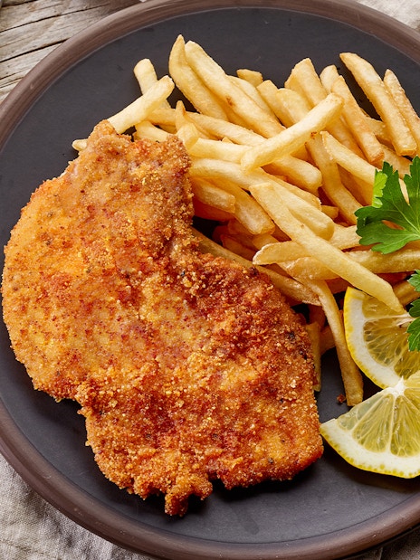 Viennese schnitzel with fries and lemon slices on a plate, Danube Canal cruise option.