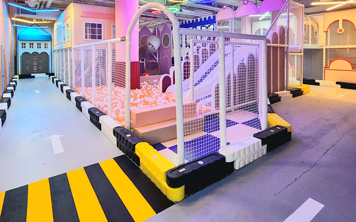 Netted play area with ball pit and slide at VroomTown Driving City.