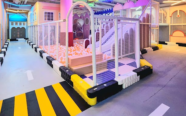 Netted play area with ball pit and slide at VroomTown Driving City.