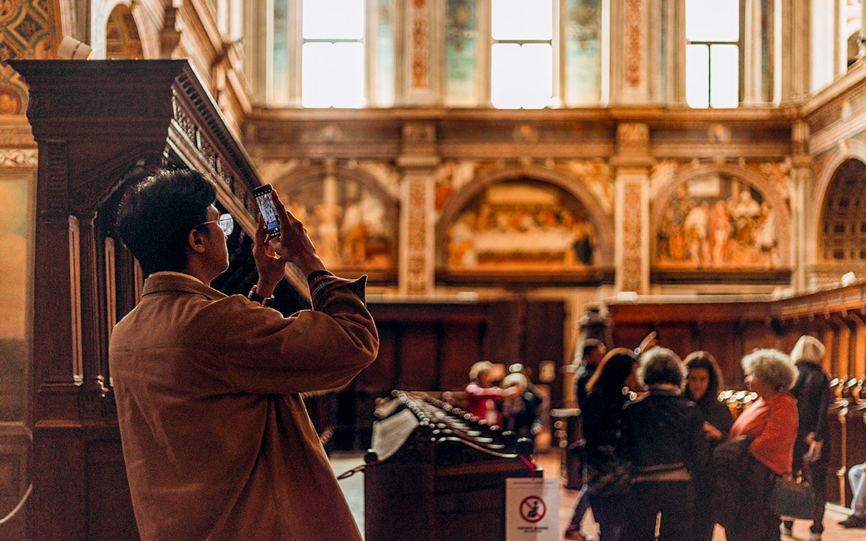 Visitor photographing The Last Supper mural in a Milan church.