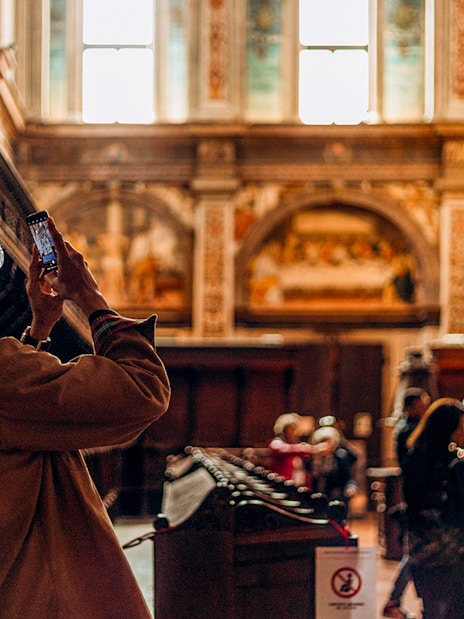 Visitor photographing The Last Supper mural in a Milan church.