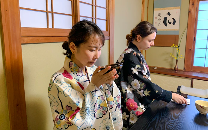 People participating in a traditional tea ceremony in Kyoto, wearing floral kimonos.
