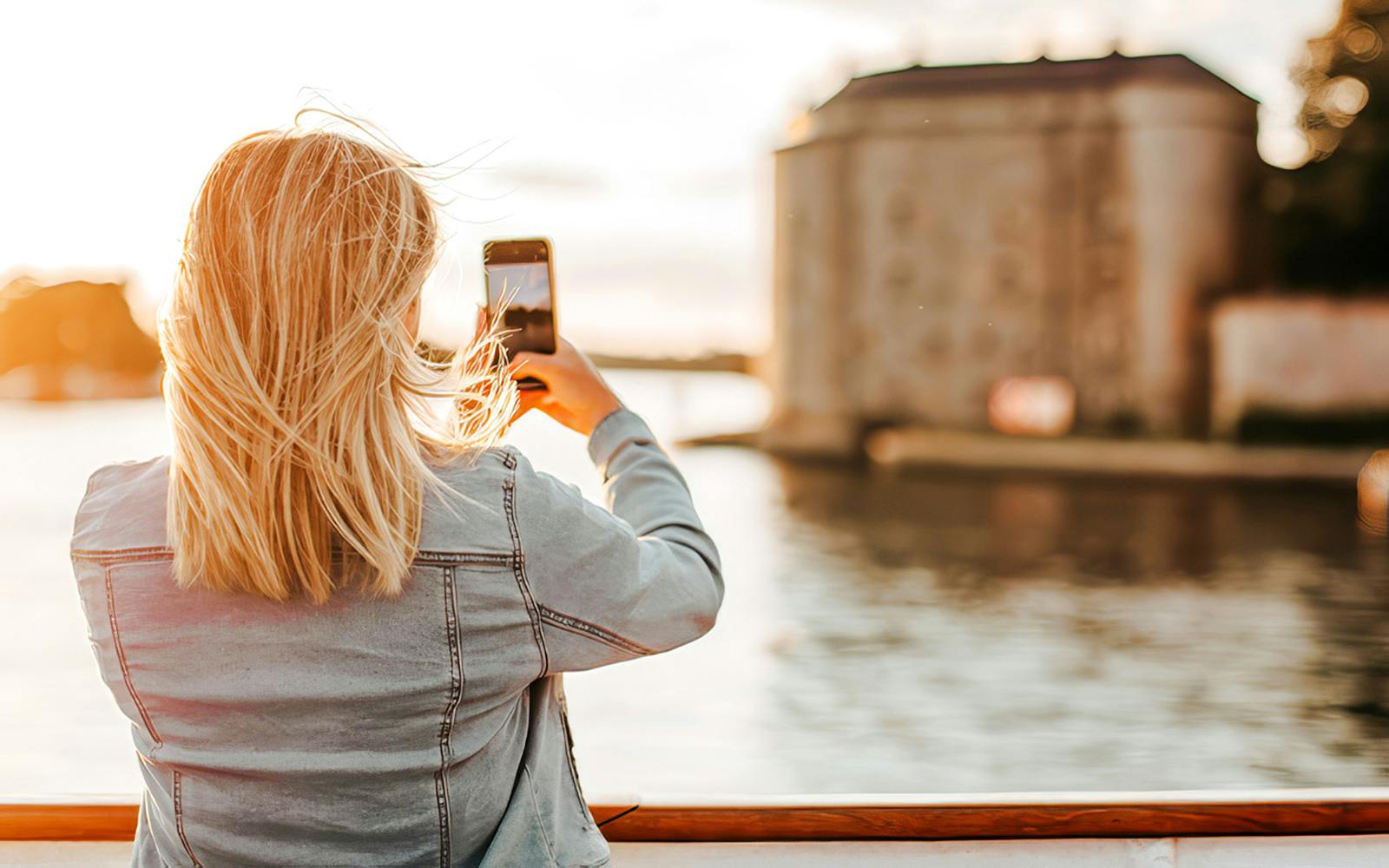 Sightseeing cruise guest photographing Stockholm archipelago landmark.