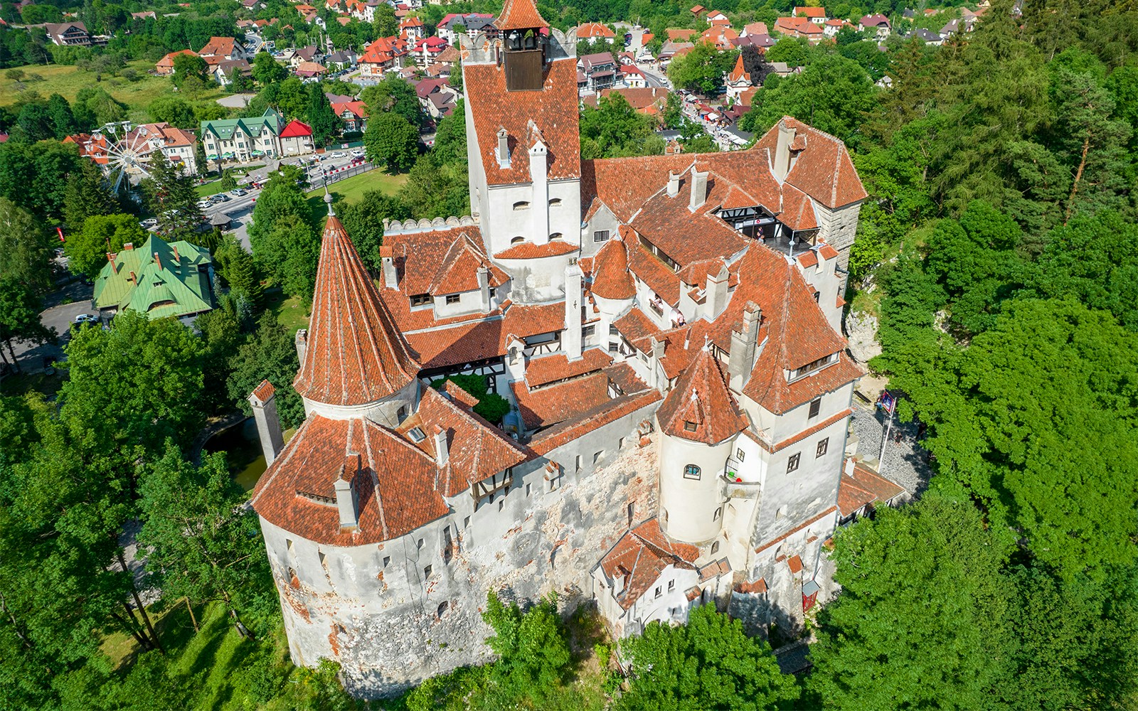 Aerial view of Bran Castle in Romania surrounded by lush greenery.