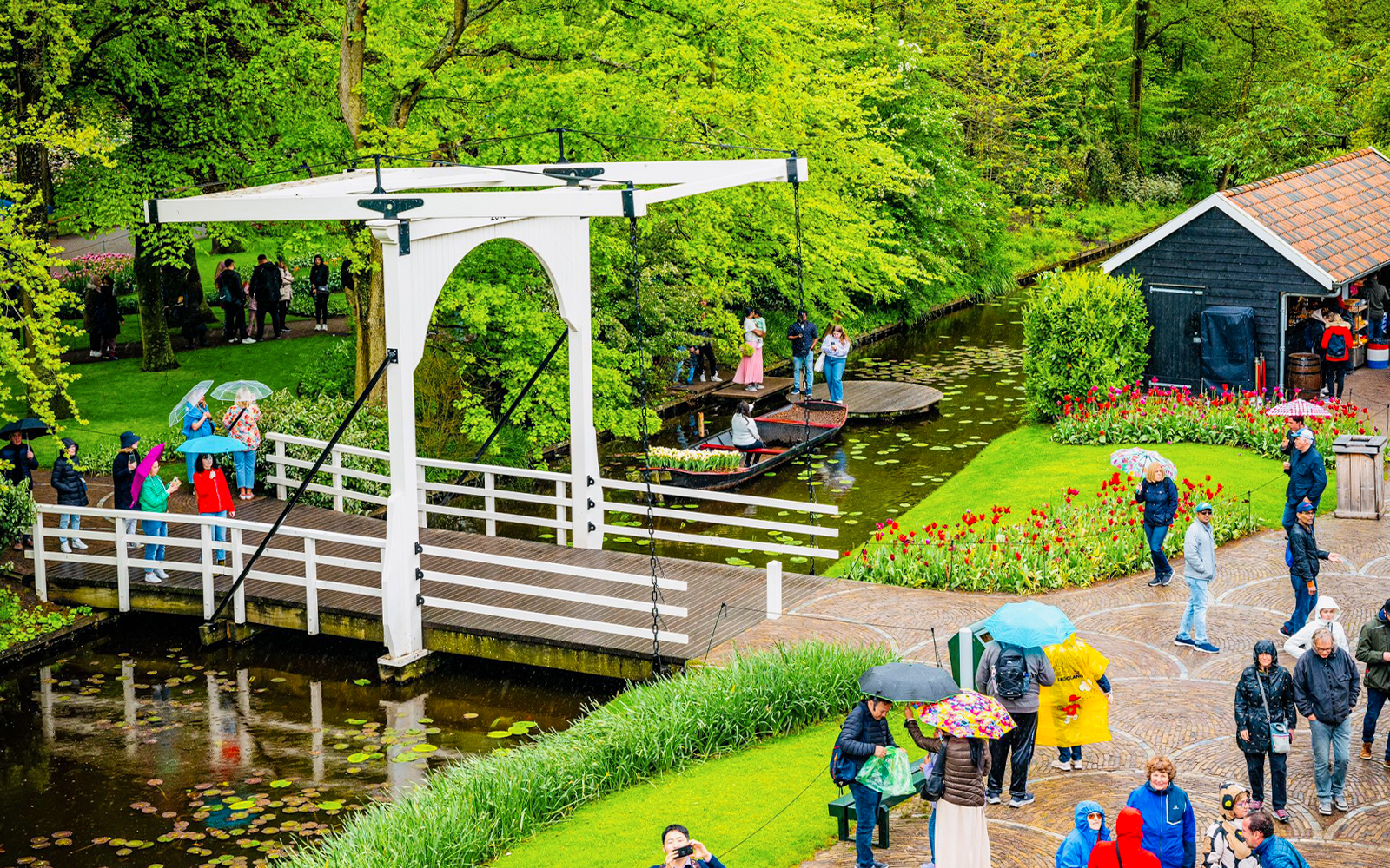 Guests exploring Tulip Experience Keukenhof with a canal, bridge, and tulip gardens.