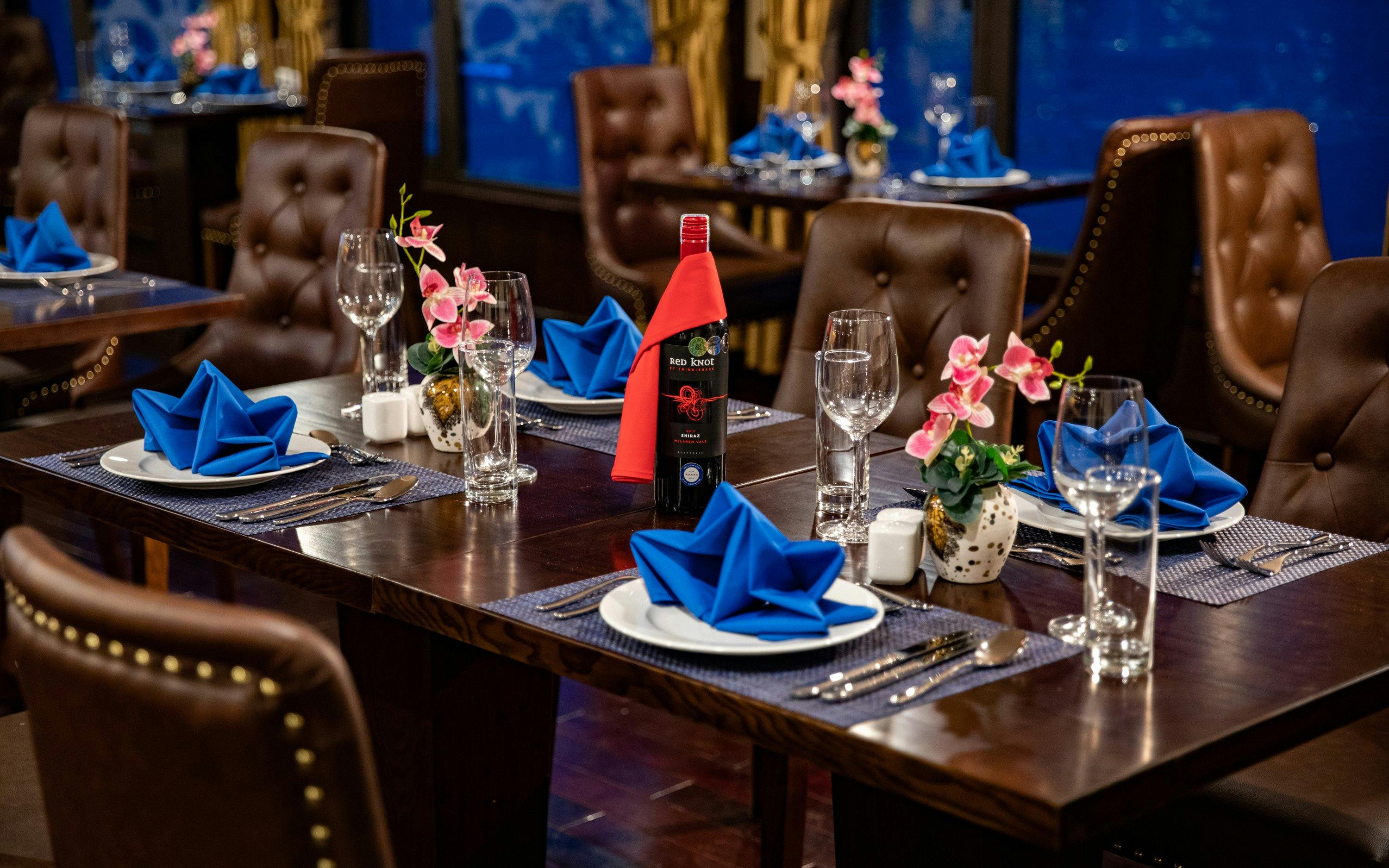 Dining setup on Lan Ha Bay cruise with blue napkins and wine bottle.