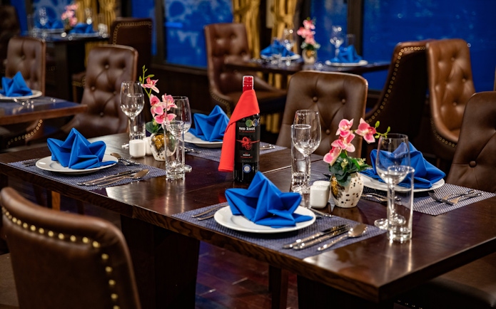 Dining setup on Lan Ha Bay cruise with blue napkins and wine bottle.
