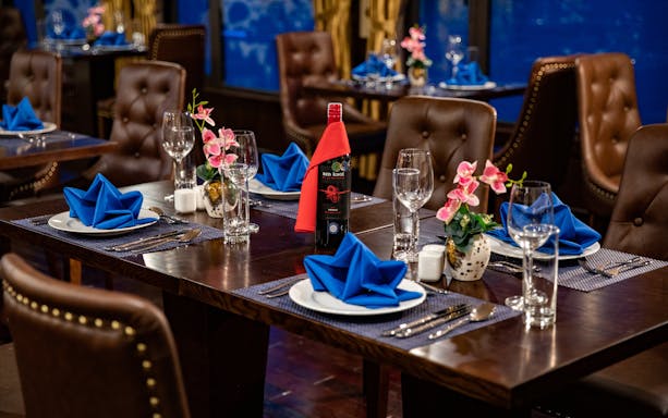 Dining setup on Lan Ha Bay cruise with blue napkins and wine bottle.