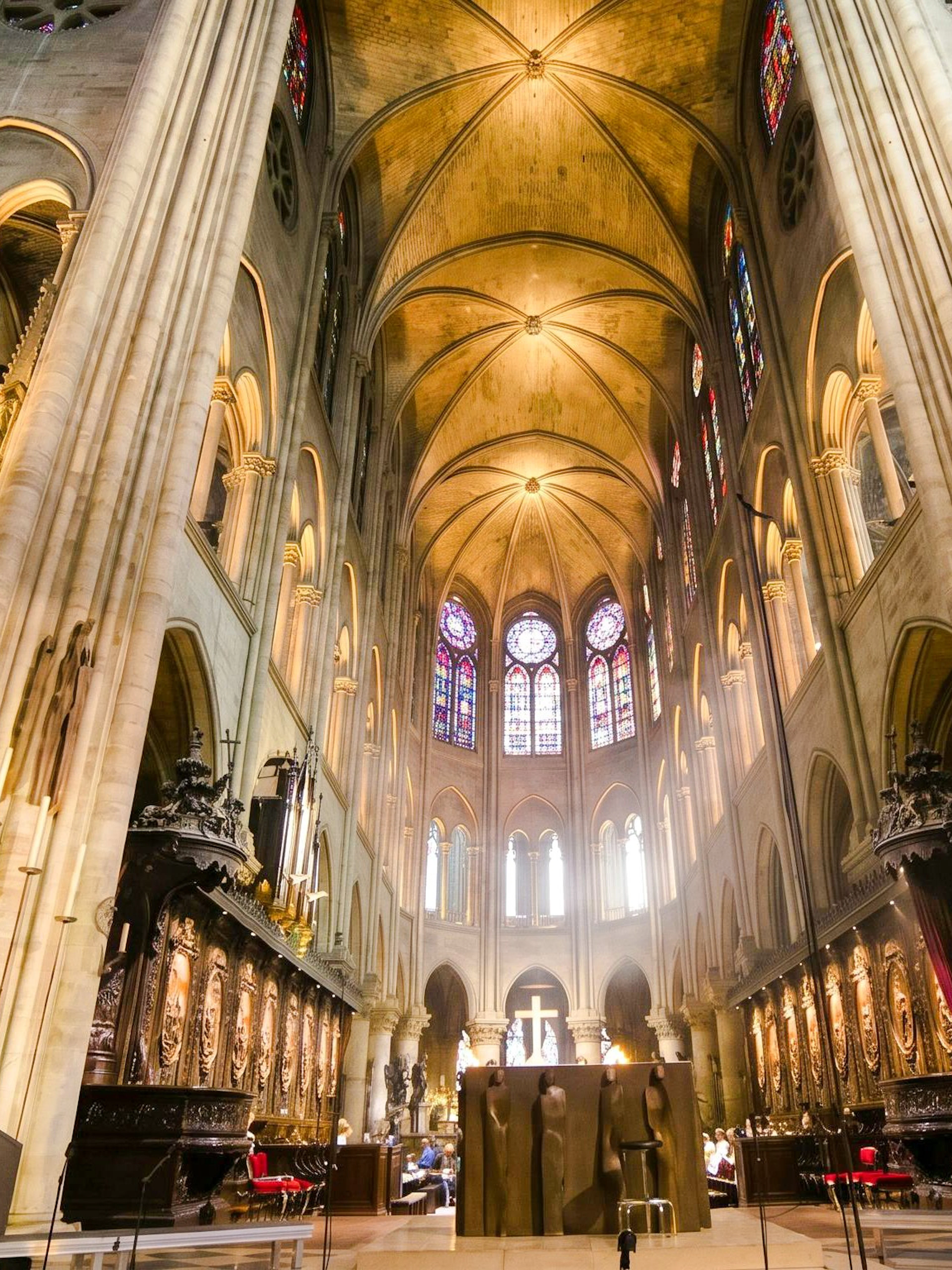 Interior view of Notre-Dame Cathedral in Paris with stained glass windows and vaulted ceilings.