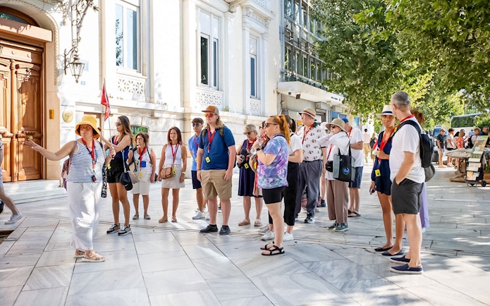 Tour group with audio guides outside Acropolis Parthenon in Athens.