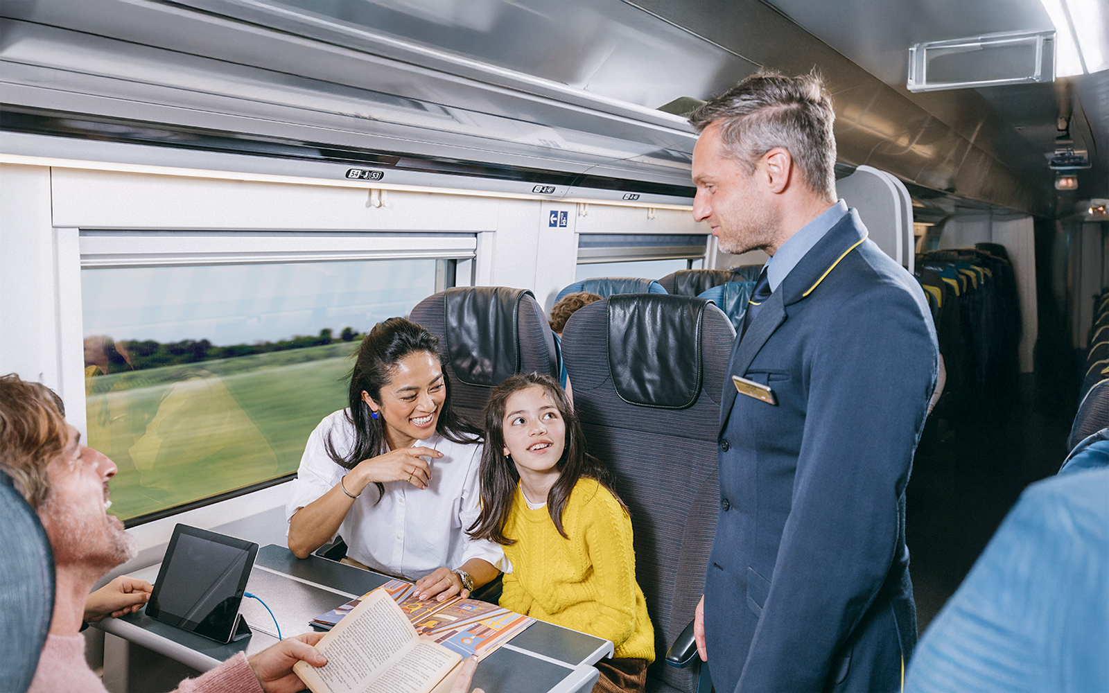 Eurostar train staff assisting family in standard class coach.