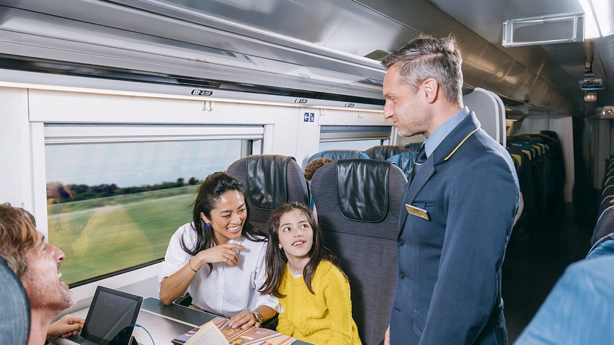 Eurostar train staff assisting family in standard class coach.