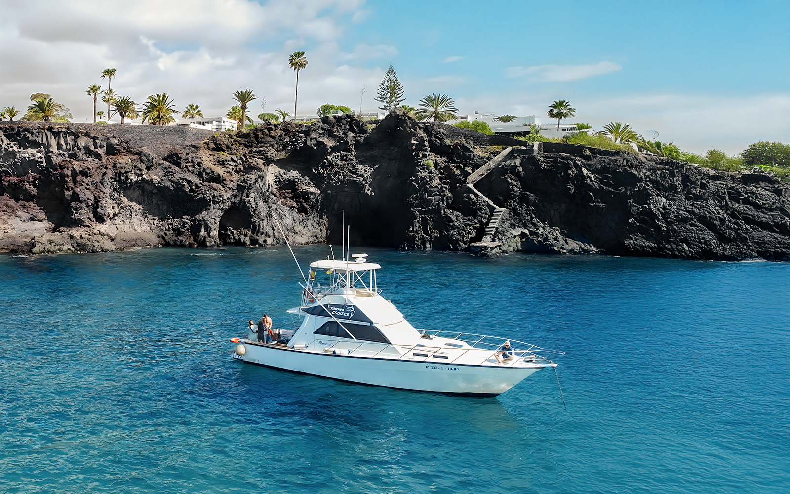 Luxury boat near rocky Tenerife coast for whale watching tour.