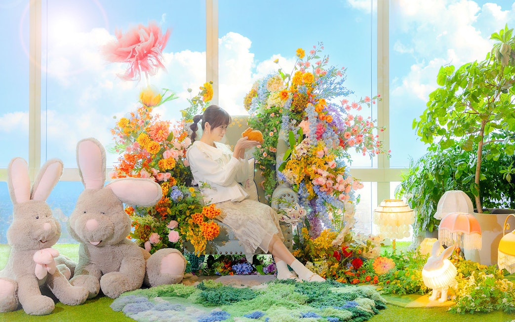 Woman surrounded by colorful flowers and plush rabbits at Taipei 101.