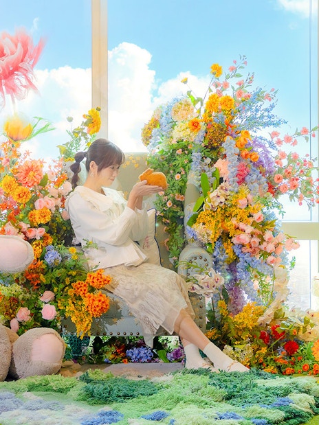 Woman surrounded by colorful flowers and plush rabbits at Taipei 101.