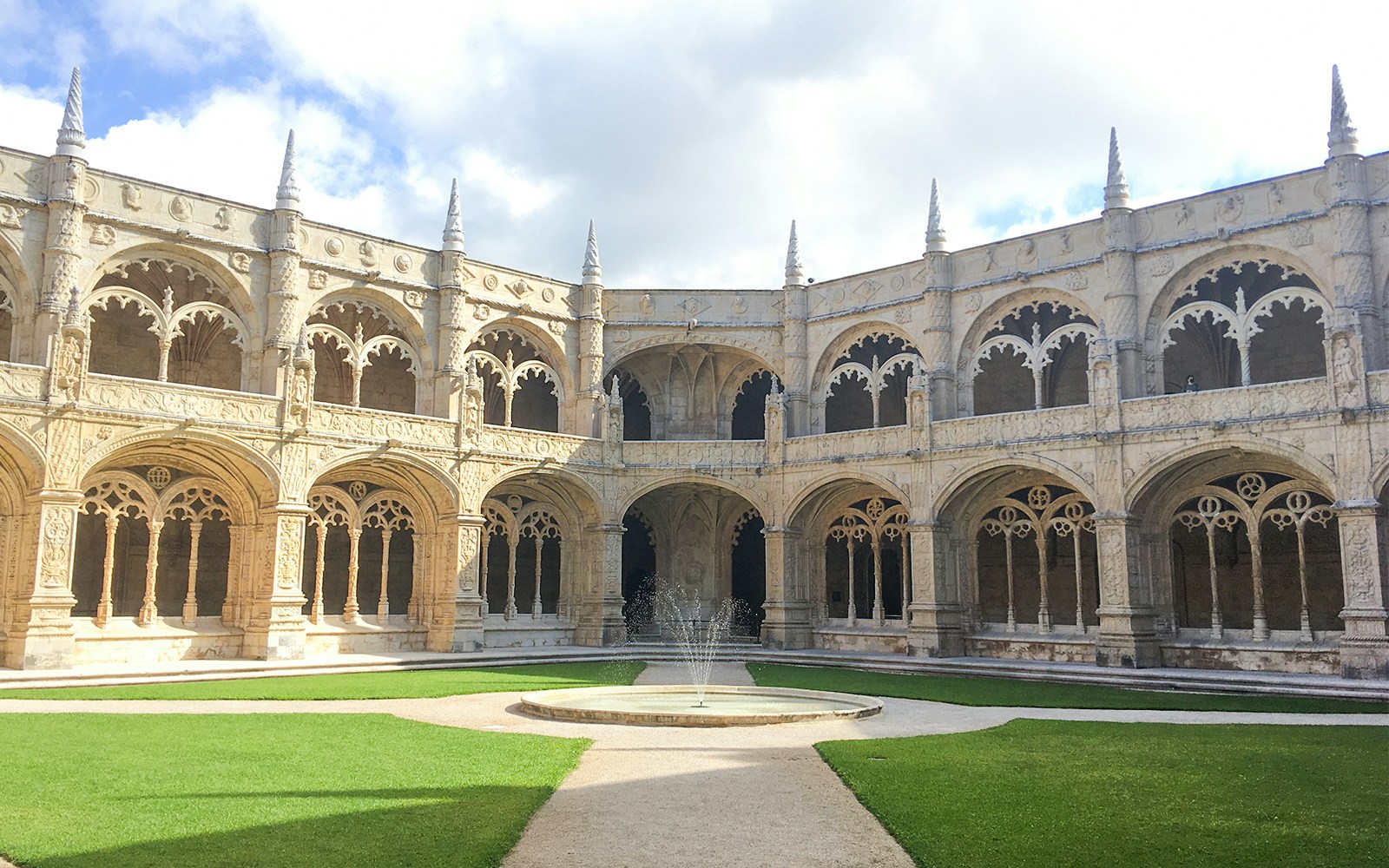 Jerónimos Monastery courtyard with ornate arches and central fountain in Lisbon, Portugal.