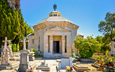 Racic Mausoleum in Cavtat graveyard surrounded by tombstones and greenery.
