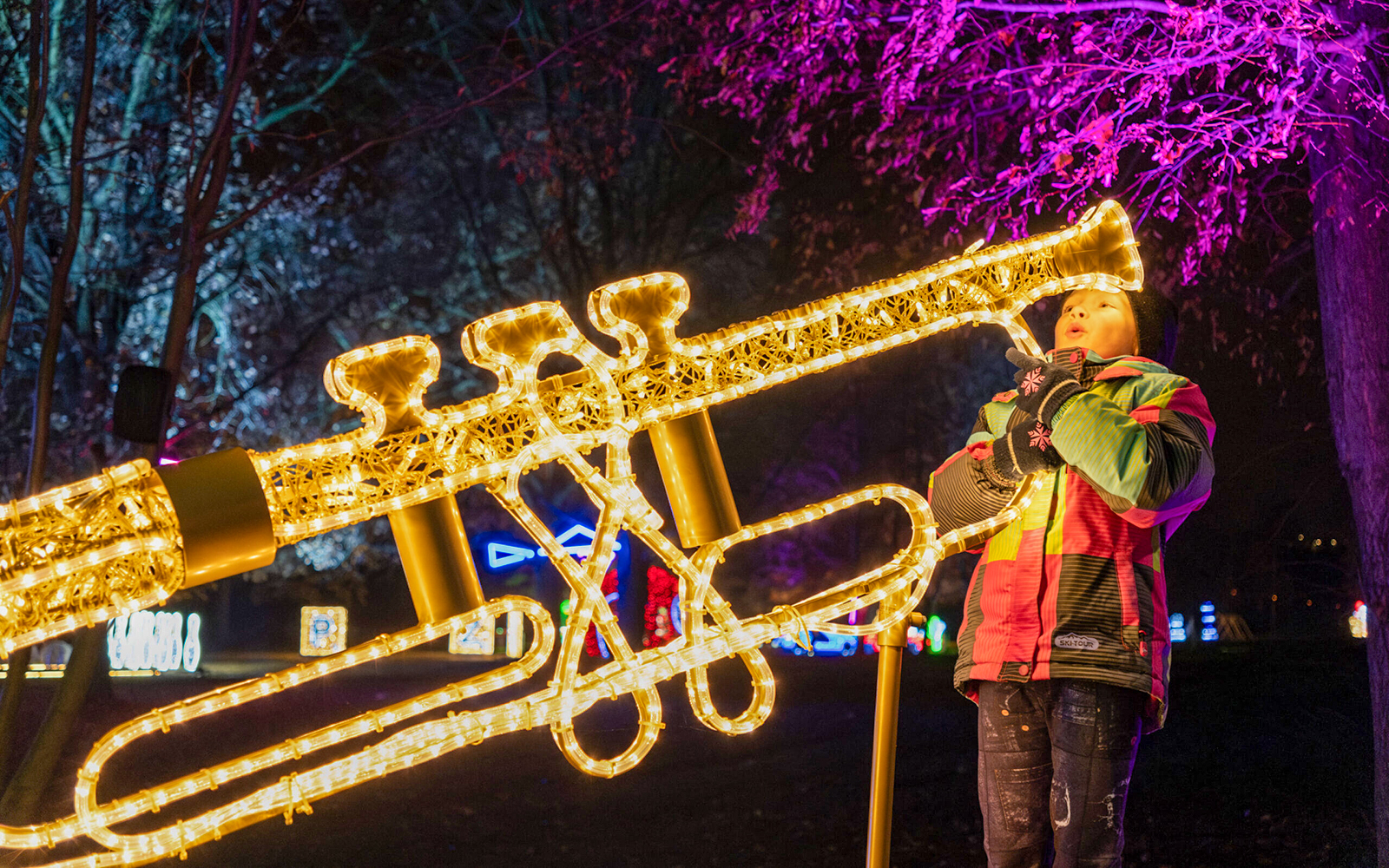 Child interacting with illuminated trumpet installation at Lumina Park Wonderworld.