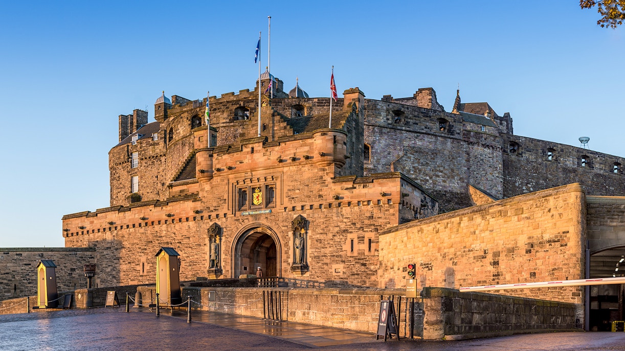 Edinburgh Castle entrance with stone walls and flags in Scotland.