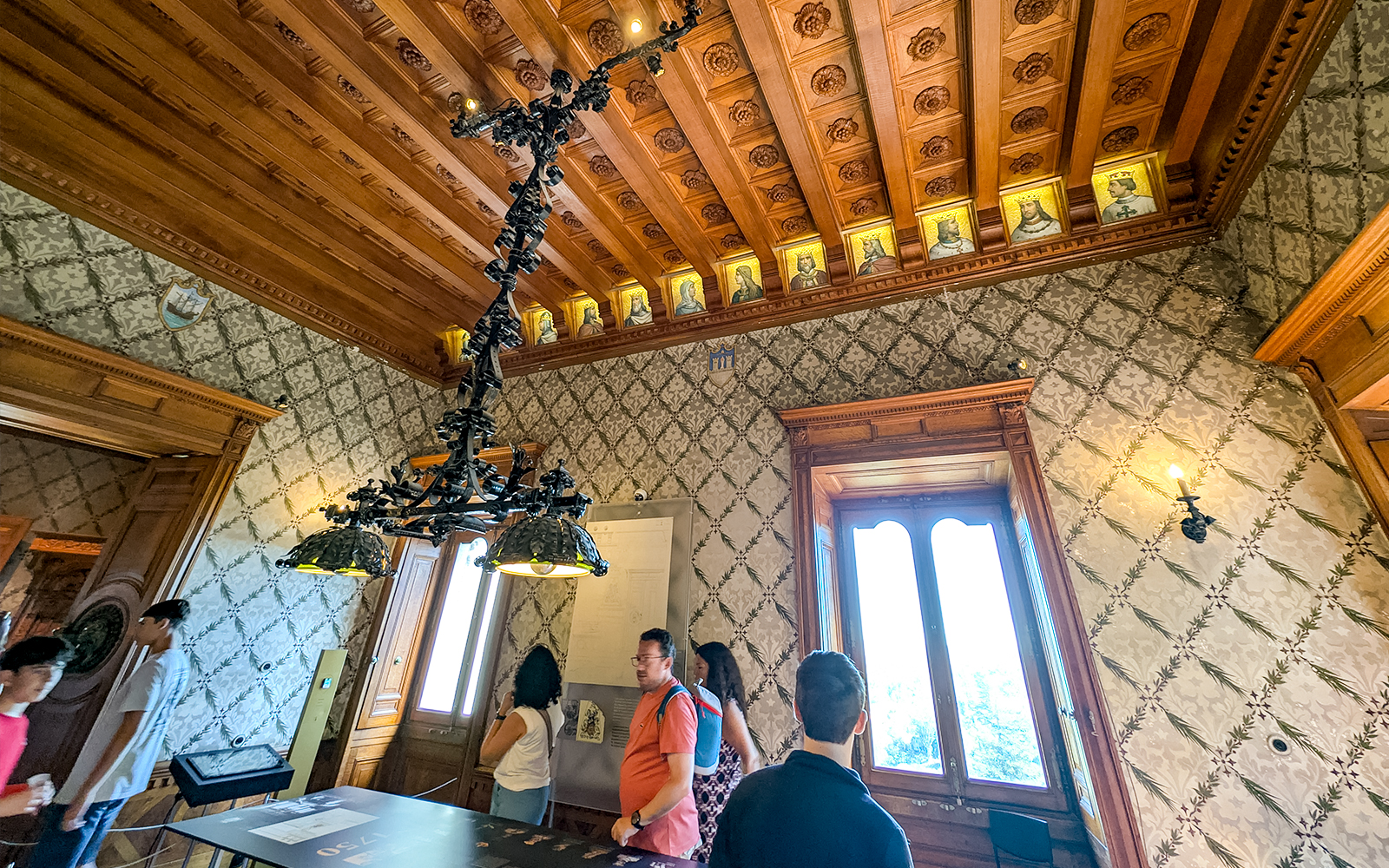 Visitors exploring an ornate room with a wooden ceiling at Quinta da Regaleira, Sintra.