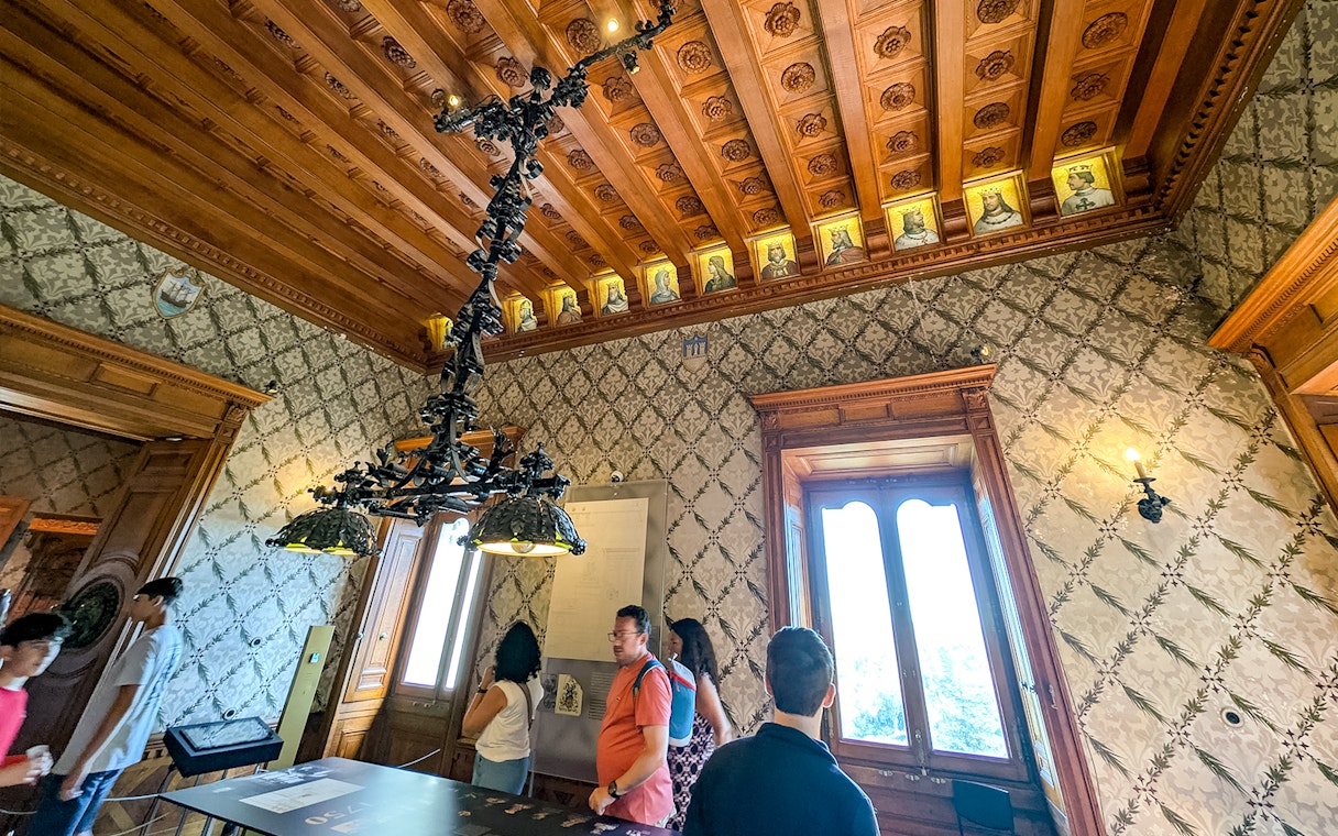 Visitors exploring an ornate room with a wooden ceiling at Quinta da Regaleira, Sintra.
