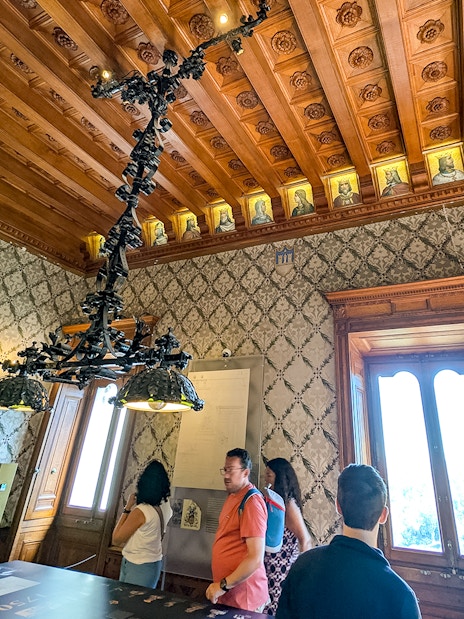 Visitors exploring an ornate room with a wooden ceiling at Quinta da Regaleira, Sintra.